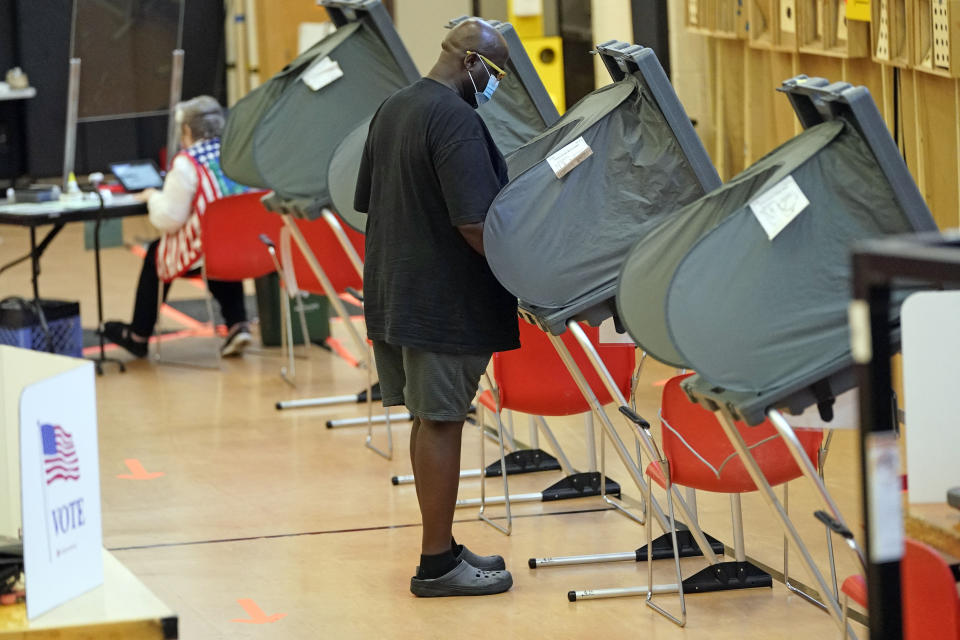 A man wears a mask while voting, Monday, June 29, 2020, in Houston. Early voting for the Texas primary runoffs began Monday. (AP Photo/David J. Phillip)