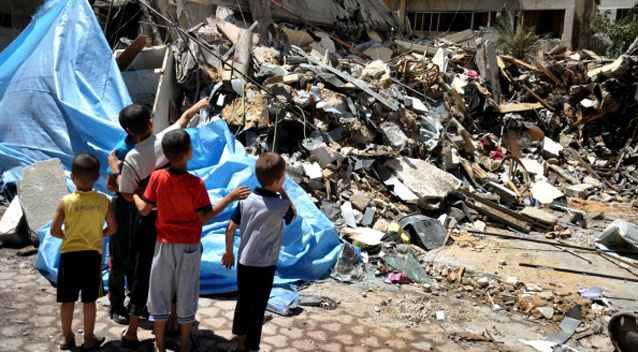 Palestinian children stare at the ruins of buildings destroyed in air attacks. (Photo: Getty)