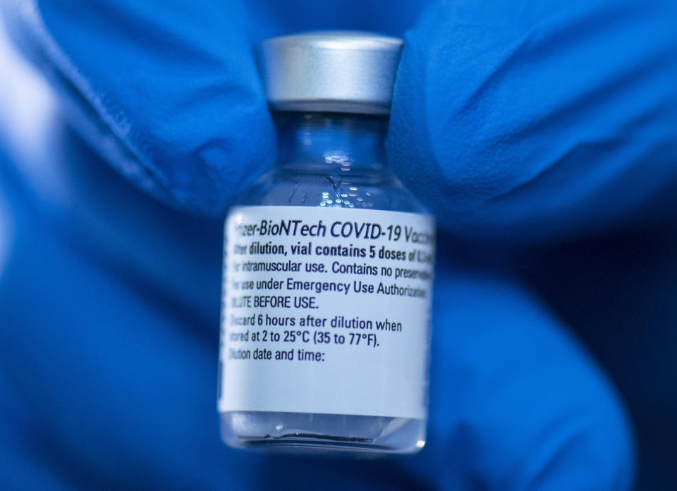 A pharmacist holds a vial of Pfizer-Biontech's Corona vaccine at the opening of the vaccination center in the Festhalle in Frankfurt, Germany, Tuesday, Jan.19, 2021. The state of Hesse operates one of its vaccination centers where thousands of people usually gather at concerts and trade fairs. (Boris Roessler/dpa via AP)