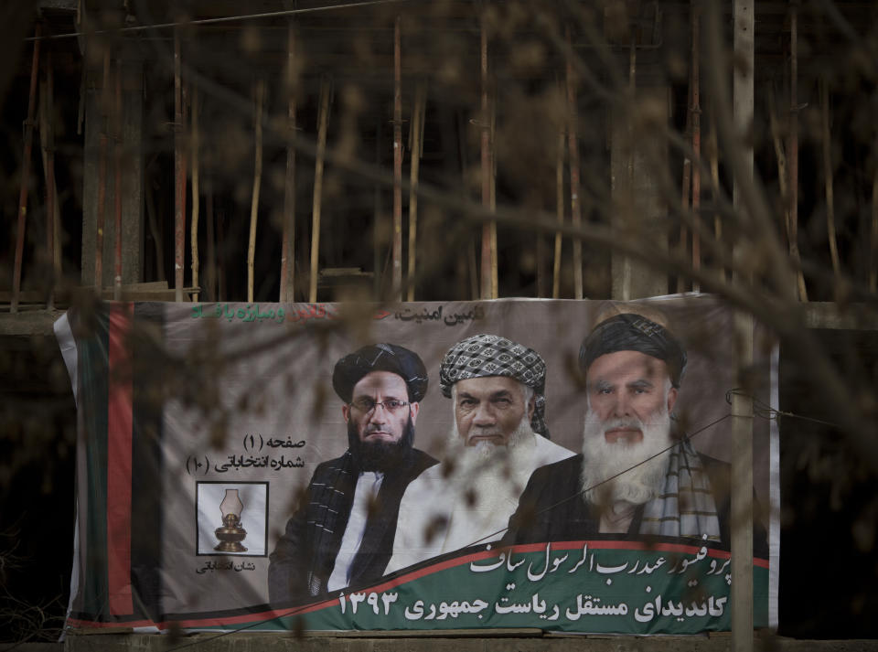 In this Friday, March 7, 2014 photo, a huge election banner with presidential hopeful Abdul Rasoul Sayyaf, right, with his running mates Ismail Khan, right, a powerful warlord from Herat and Abdul Wahab Erfan, a parliamentarian, hangs from a construction building in Kabul, Afghanistan. During Afghanistan’s civil war in the early 1990s, Sayyaf’s militia killed tens of thousands of Hazaras, a community who are mostly Shiite Muslims, considered infidels by the Sunni radical fighters in Sayyaf’s forces. Still, many of the candidates or their running mates have violent histories. Several have been named by the U.S.-based Human Rights Watch as responsible for mass killings during the 1992 to 1996 civil war, fought between Islamic insurgents turned warlords who turned their guns on each other after throwing out the invading Soviet military. (AP Photo/Anja Niedringhaus)