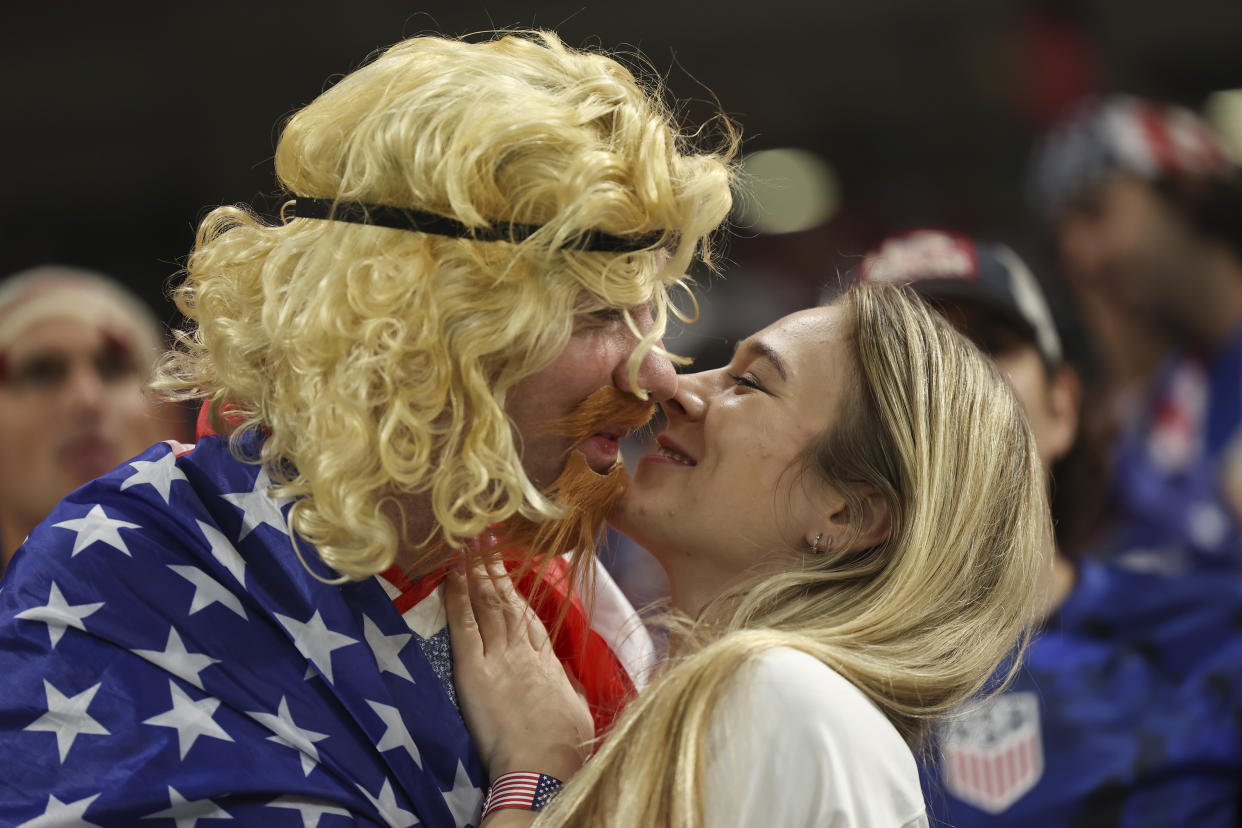 DOHA, QATAR - NOVEMBER 29: A fan of USA dressed as former USA player Alexi Lalas embraces a female USA fan during the FIFA World Cup Qatar 2022 Group B match between IR Iran and USA at Al Thumama Stadium on November 29, 2022 in Doha, Qatar. (Photo by Matthew Ashton - AMA/Getty Images)