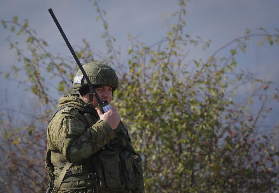 A Russian peacekeeper speaks on a satellite phone at a checkpoint on the road to Shusha in the separatist region of Nagorno-Karabakh, on Tuesday, Nov. 17, 2020. Russian peacekeepers have started to move into the region, a total of 1,960 of them are to be sent in under a five-year mandate. Russia's Defense Ministry reported that the peacekeepers accompanied about 1,200 people returning to Nagorno-Karabakh from Armenia since Saturday. (AP Photo/Sergei Grits)