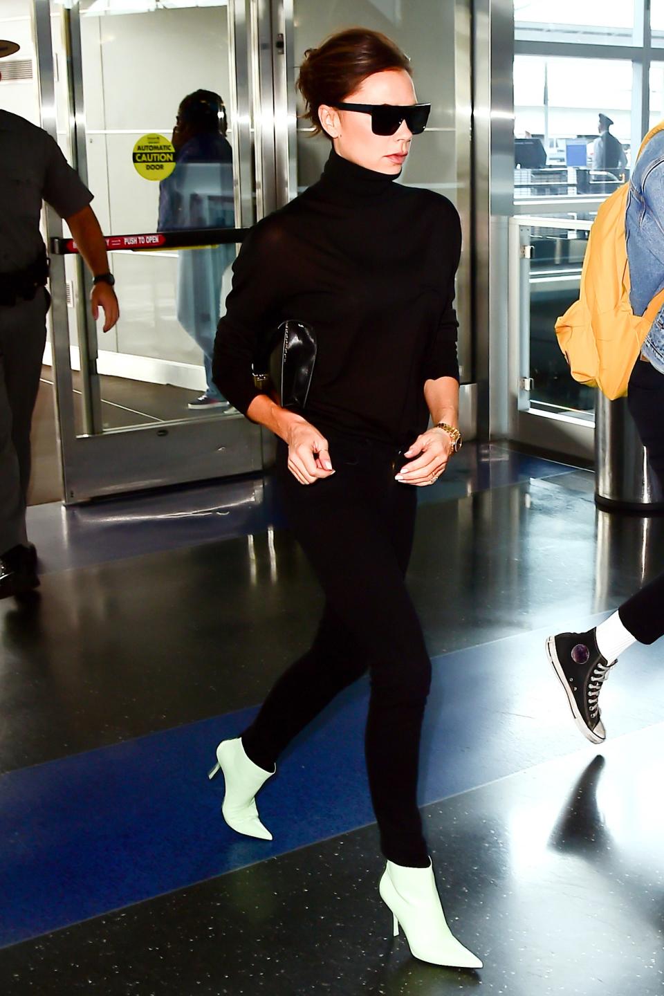 The Beckham way to hit the airport: black frames, black separates, and flashy white boots.