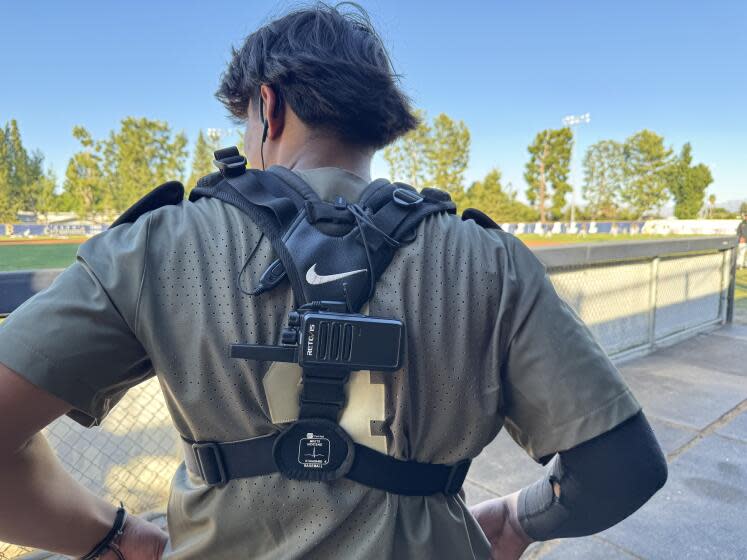 Harvard -Westlake catcher Andrew Rico has a hearing device in his ear and a walkie-talkie fastened to his back