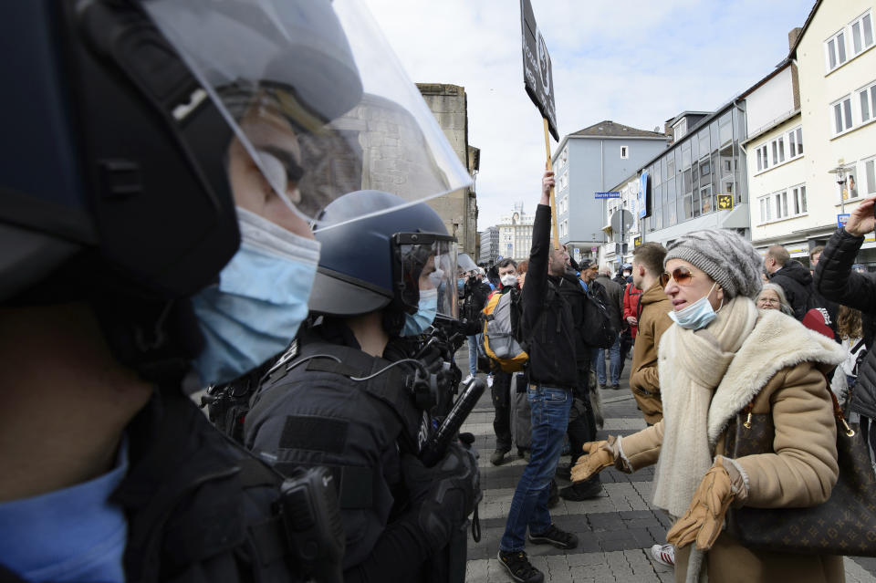 A woman speaks to police officers on duty at a rally under the motto "Free citizens Kassel - basic rights and democracy" in Kassel, Germany, Saturday, March 20, 2021. According to police, several thousand people were on the move in the city center and disregarded the instructions of the authorities during the unregistered demonstration against Corona measures. (Swen Pfoertner/dpa via AP)