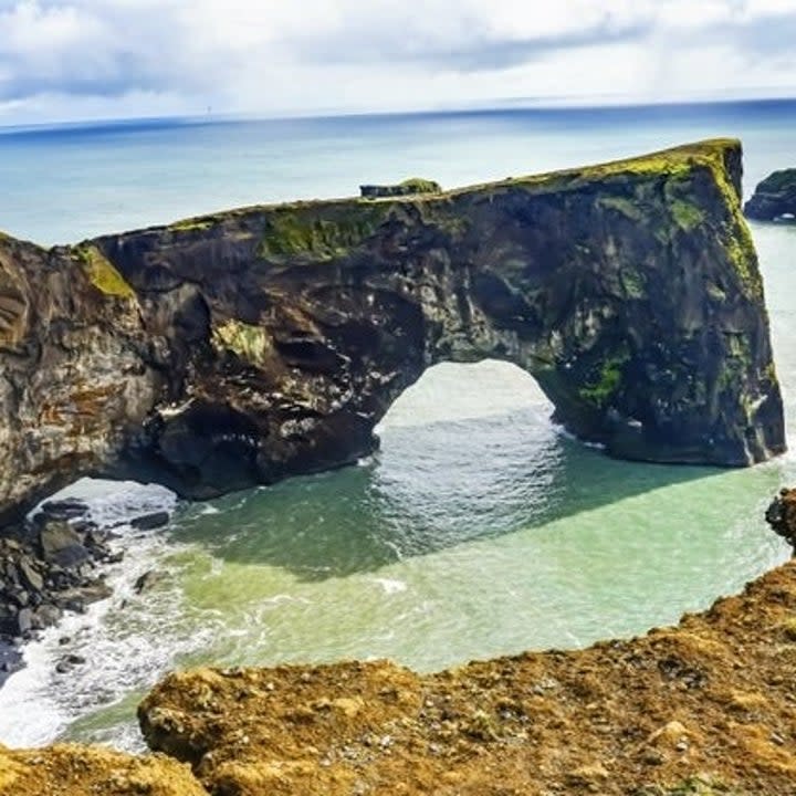 The black sand beaches are back, and this time, they brought a rock arch. Dyrhólaey is on the south shore of Iceland, and there's even a quaint lighthouse nearby.