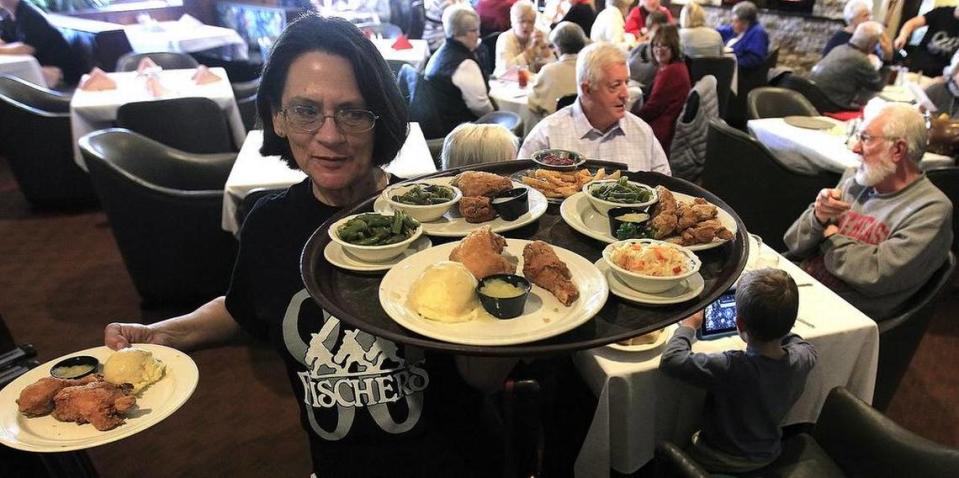 Elaine Jagla, a Fischer’s employee for the past seven years, takes plates of food to patrons in the dining room.