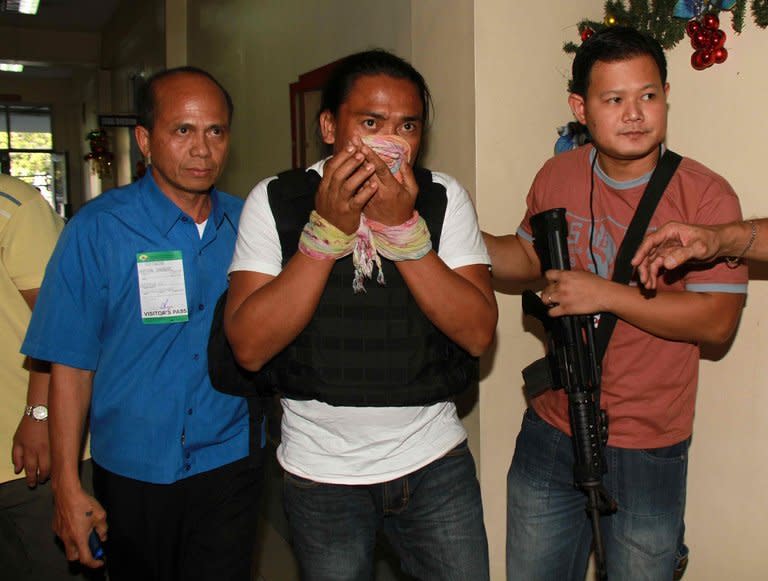 Maguindanao massacre suspect Bong Andal (centre), is escorted at Ninoy Aquino International Airport in Manila on November 27, 2012. A backhoe driver has described in chilling detail how he used the excavator to bury the 58 victims of the Philippines' worst political massacre, according to a copy of his deposition obtained by AFP Tuesday