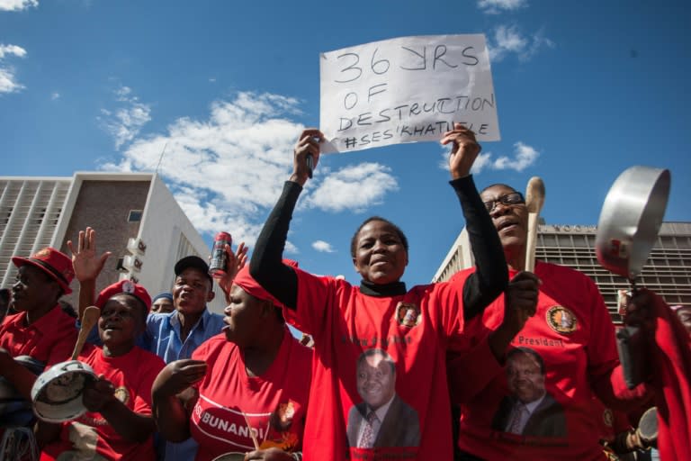 A woman holds a placard referring to the 36 years of rule by President Robert Mugabe as elderly Zimbabwean women beat pots during a demonstration in Bulawayo