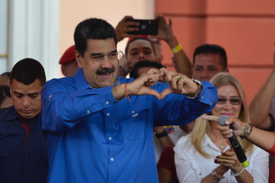 Venezuela's President Nicolas Maduro, accompanied by first lady Cilia Flores, flashes a heart-hand symbol at supporters during an event at the Miraflores Presidential Palace to mark Youth Day, in Caracas, Venezuela, Wednesday, Feb. 12, 2020. (AP Photo/Matias Delacroix)