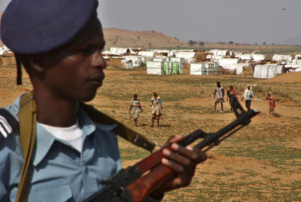 FILE - In this Aug. 25, 2004 file photo, a Sudanese policeman stands guard at Abu Shouk camp, in North Darfur, Sudan, where more than 40 thousand displaced people receive food and shelter from international aid agencies. Former Sudanese President Omar al-Bashir, driven from power in April 2019, and now languishing in a prison where his opponents were once jailed and tortured, is more vulnerable than ever to a decade-old international arrest warrant for war crimes committed in Darfur. But the military, which forced him from power after four months of mass protests, has said it will not extradite him to the International Criminal Court at the Hague. (AP Photo/Amr Nabil, File)