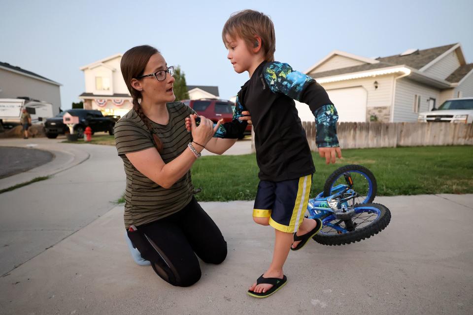 Kerra Davis helps her son Reed Davis after he fell off his bike outside their home in West Jordan on Friday, July 21, 2023. Davis, a mother of three, uses medical cannabis to treat chronic pain from endometriosis, pelvic congestion syndrome and arthritis. | Kristin Murphy, Deseret News