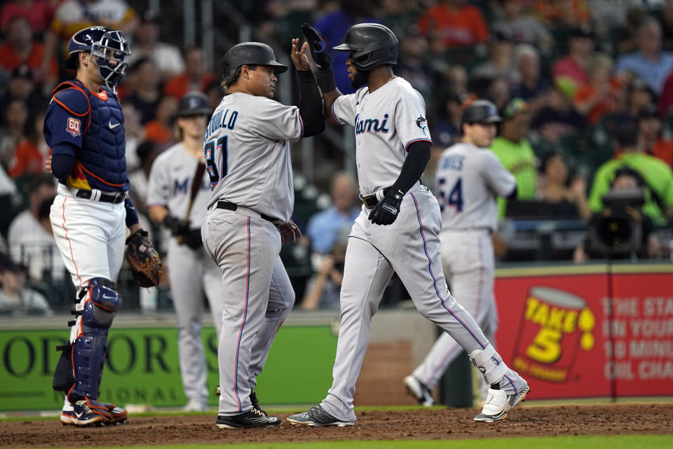 Miami Marlins' Bryan De La Cruz, right, celebrates with Willians Astudillo (37) after both scored on De La Cruz's three-run home run as Houston Astros catcher Jason Castro, left, stands behind home plate during the seventh inning of a baseball game Sunday, June 12, 2022, in Houston. (AP Photo/David J. Phillip)