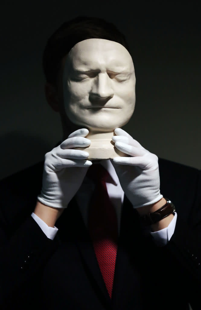 A person holding the mask up in front of their face: eyes closed, eyebrows furrowed, and thin lips