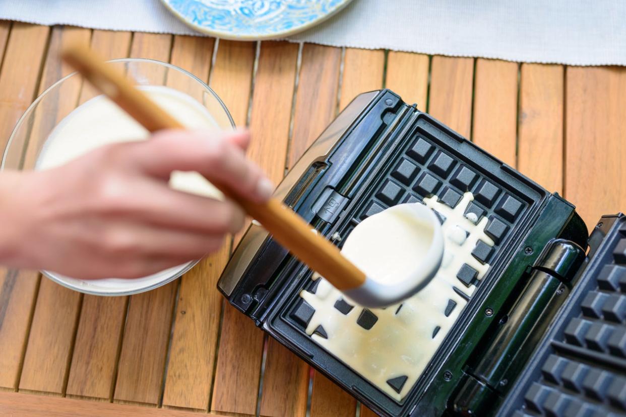 Preparation of homemade waffles. Pouring dough into waffle irons