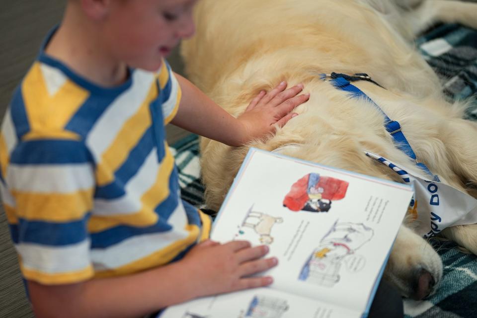 PJ Kelly, 8, reads to Paws and Think therapy dog Cooper on Wednesday, Nov. 8, 2023, after meeting IndyStar for an interview at Brownsburg Public Library. Paws and Think is a program where children can practice their reading in front of therapy dogs, which creates a more welcoming, less intimidating environment.