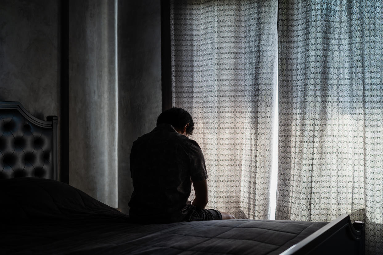 A man sitting on a bed in a dark room.