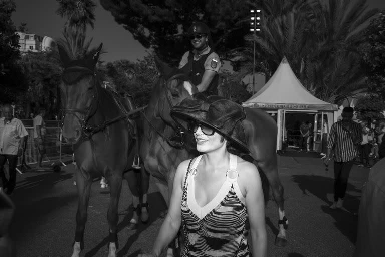 Una mujer camina por la Croisette frente a un policía a caballo durante el 75º Festival internacional de cine en Cannes, el sábado 21 de mayo de 2022