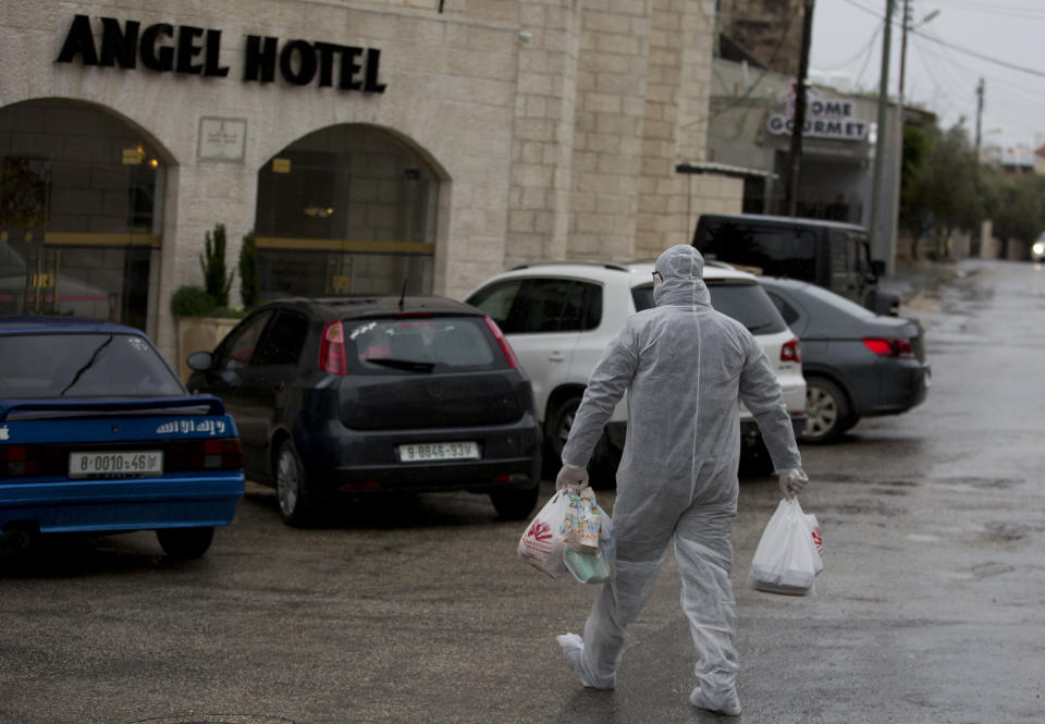 Palestinian policeman delivers supplies to the hotel staff which tested positive to coronavirus to a hotel in Bethlehem, West Bank, Friday, March 6, 2020. Foreign tourists say they are being denied entry to the biblical West Bank city of Bethlehem a day after Israeli and Palestinian authorities took measures to prevent the spread of the new coronavirus. (AP Photo/Majdi Mohammed)