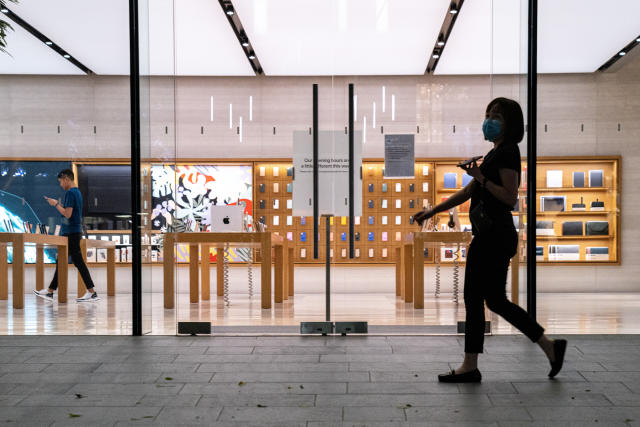 SINGAPORE, SINGAPORE - cA woman wearing a protective mask walk past an empty flagship Apple retail store on Orchard Road on March 15, 2020 in Singapore. The store is temporarily closed after Apple announced that it is closing all stores outside Greater China for 2 weeks due to the coronavirus. (Photo by Ore Huiying/Getty Images)