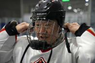A member of the "1979" hockey club puts on his helmet during a break between periods in a hockey match at a rink in Beijing, Wednesday, Jan. 12, 2022. Spurred by enthusiasm after China was awarded the 2022 Winter Olympics, the members of a 1970s-era youth hockey team, now around 60 years old, have reunited decades later to once again take to the ice. (AP Photo/Mark Schiefelbein)