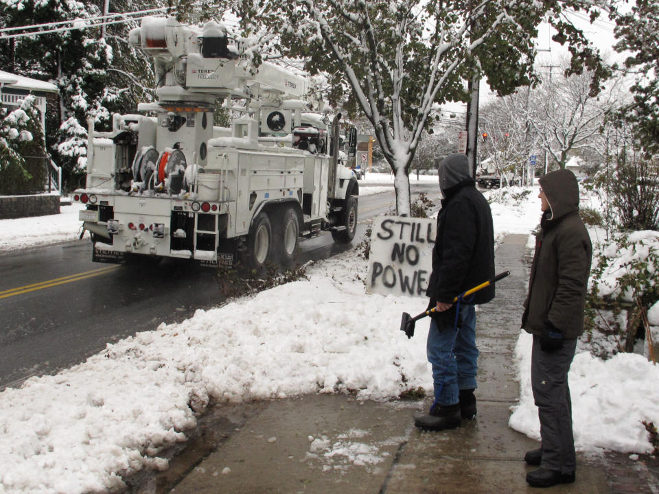 Vincent and Jeanmarie Pina watch as a power truck from Burbank, Calif. passes their still darkened home on Thursday, Nov. 8, 2012 in Farmingdale, N.Y. The couple said they have remained in their home for 11 days waiting for their lights to come back on.(AP Photo/Frank Eltman)