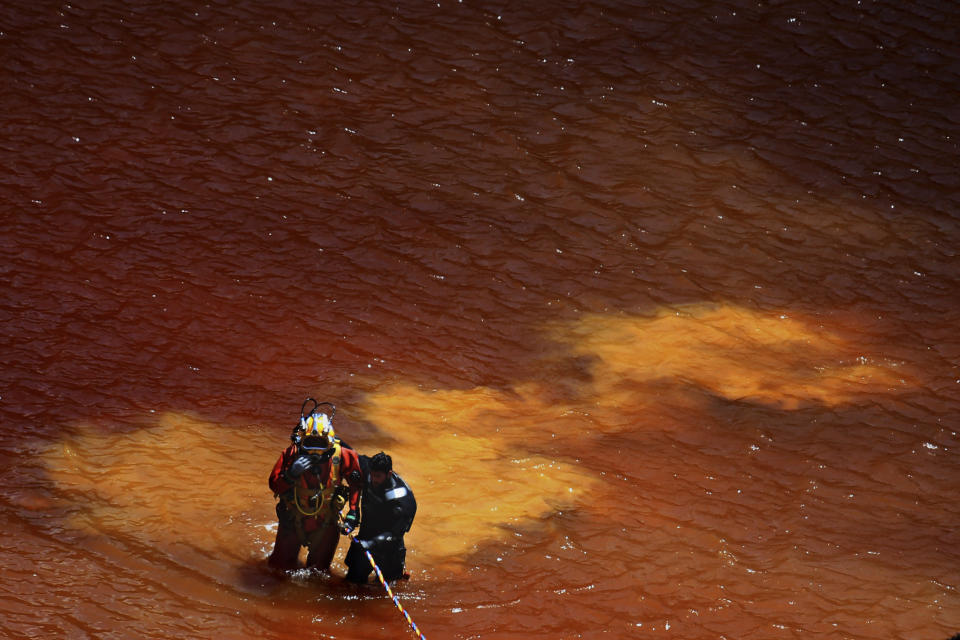 A diver takes a help from his colleague after a dive in a toxic man-made lake during a search for a third suitcase near the village of Mitsero outside of the capital Nicosia, Cyprus, Tuesday, May 7, 2019. New police chief Kypros Michailides has apologized to the families of seven foreign women and girls who an army captain has confessed to killing. (AP Photo/Petros Karadjias)