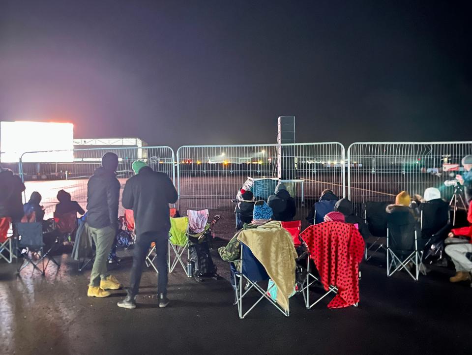 People set up chairs at fence at Spaceport Cornwall
