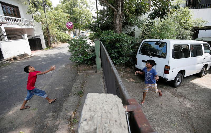 Two children play over a boundary wall of a house during the curfew in Colombo