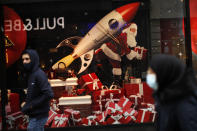 People, wearing face masks to prevent the spread of the coronavirus, walk past a shopping mall display windows with Christmas decoration in a commercial street in downtown Brussels, Tuesday, Dec. 1, 2020. Non-essential shops in Belgium are reopening on Tuesday in the wake of encouraging figures about declining infection rates and hospital admissions because of the coronavirus. (AP Photo/Francisco Seco)