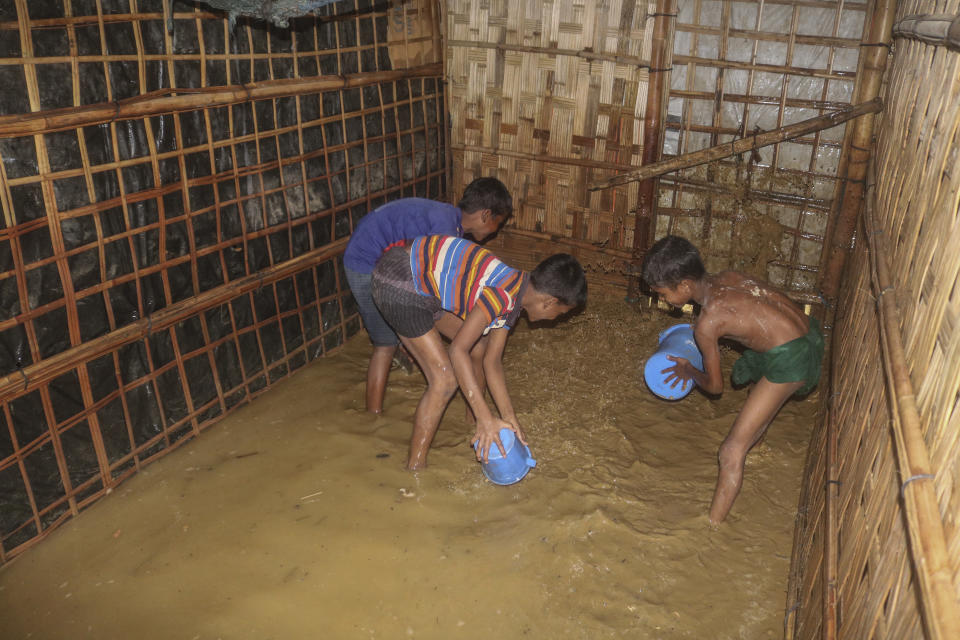 Rohingya refugee children try to pour away flood water from their homes at the Rohingya refugee camp in Kutupalong, Bangladesh, Wednesday, July 28, 2021. Days of heavy rains have brought thousands of shelters in various Rohingya refugee camps in Southern Bangladesh under water, rendering thousands of refugees homeless. (AP Photo/ Shafiqur Rahman)