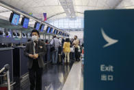 In this March 26, 2019 photo, passengers wait at the check-in counter of Cathay Pacific Airways at the Hong Kong International Airport. Cathay Pacific Airways is acquiring Hong Kong-based budget airline HK Express. Cathay said Wednesday, March 27, 2019, it will pay 4.93 billion Hong Kong dollars ($628 million) for HK Express. It said the acquisition will retain its identity as a separate brand and be operated as a low-cost carrier. (AP Photo/Kin Cheung)