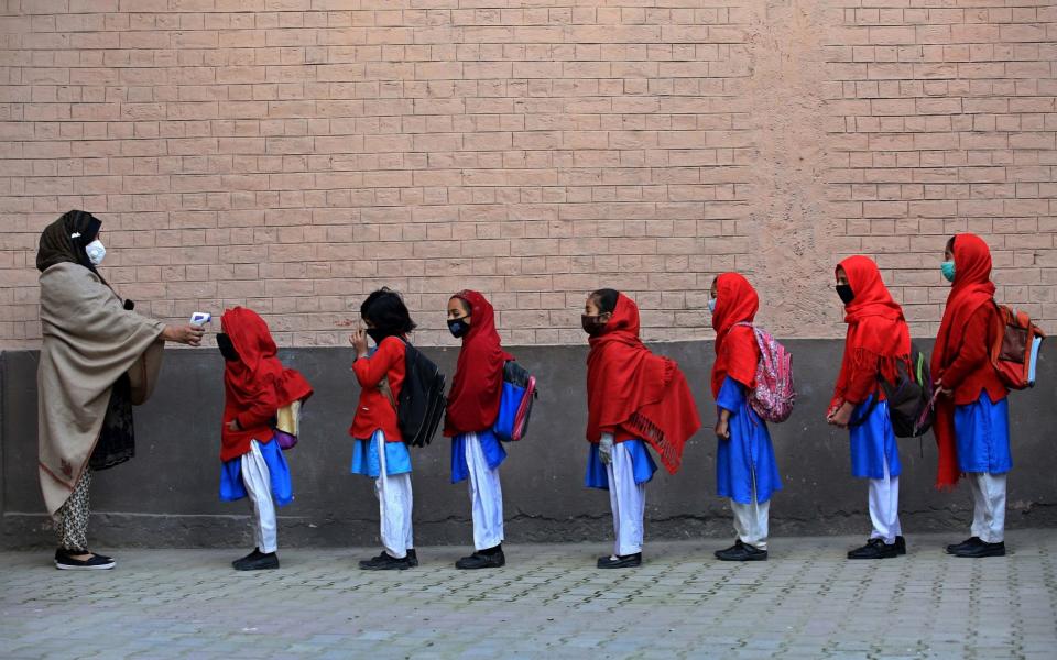 School staff check the temperatures of students as they arrive on the first day of primary school, after the resumption of classes in Peshawar - BILAWAL ARBAB/EPA-EFE/Shutterstock 