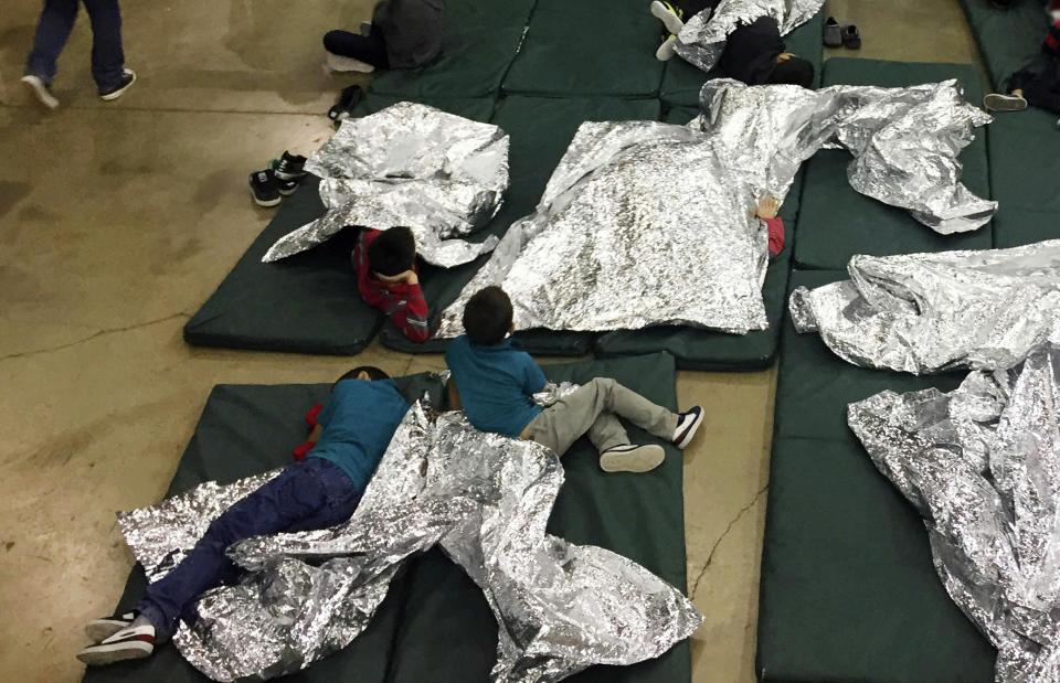 FILE - In this Sunday, June 17, 2018, file photo provided by U.S. Customs and Border Protection, people who've been taken into custody related to cases of illegal entry into the United States rest in one of the cages at a facility in McAllen, Texas. A federal volunteer at the Biden administration's largest shelter for unaccompanied immigrant children says paramedics were called regularly during her the two weeks she worked there. She said panic attacks would occur often after some of the children were taken away to be reunited with their families, dashing the hopes of those left behind. The conditions described by the volunteer highlight the stress of children who cross the U.S.-Mexico border alone and now find themselves held at unlicensed mass-scale facilities waiting to reunite with relatives. (U.S. Customs and Border Protection's Rio Grande Valley Sector via AP, File)