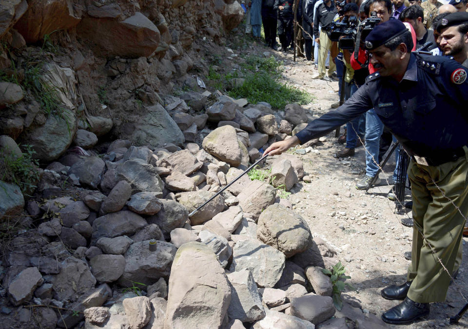 A police officer points to a munition fired by Indian forces that landed in Nosehri village on the Line of Control that divides Kashmir between Pakistan India, near Muzaffarabad, Pakistan, Sunday, Aug. 4, 2019. Tensions have soared along the volatile, highly militarized frontier between India and Pakistan in the disputed Himalayan region of Kashmir, as India deployed more troops and ordered thousands of visitors out of the region. (AP Photo/M.D. Mughal)