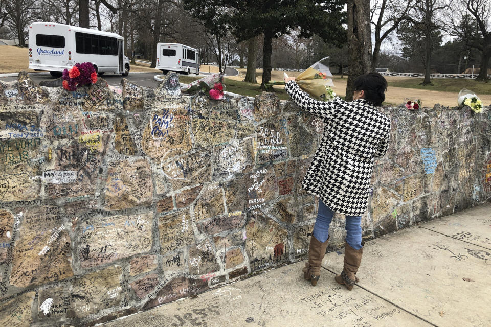 Una admiradora coloca un ramo de flores sobre una pared de piel fuera de Graceland el 13 de enero de 2023 en Memphis, Tenneseee. Lisa Marie Presley será enterrada en Graceland, la famosa mansión de Elvis Presley que el viernes se convirtió en un punto de reunión para los fans conmovidos por la muerte de la hija del rey del rock and roll ocurrida un día antes. (AP Photo/Adrian Sainz)