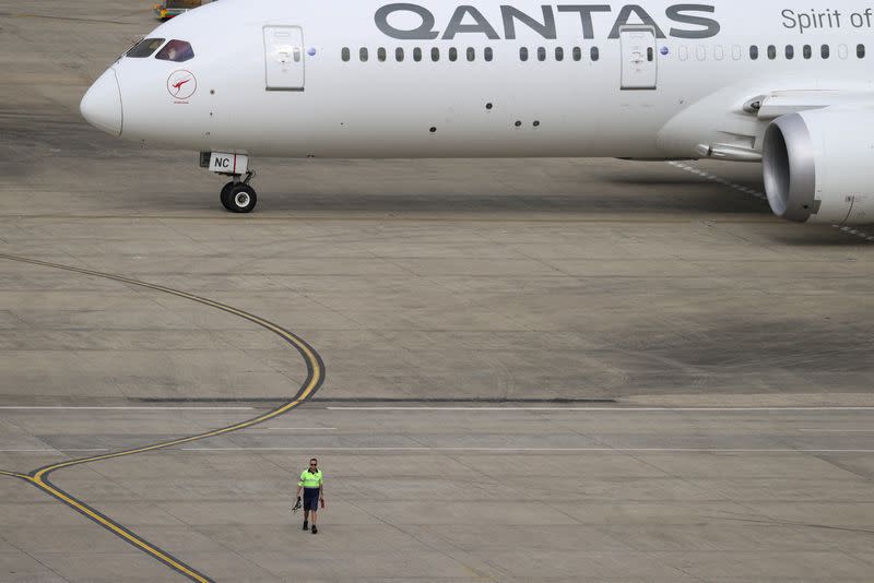 FILE PHOTO: A ground worker walking near a Qantas plane is seen from the international terminal at Sydney Airport