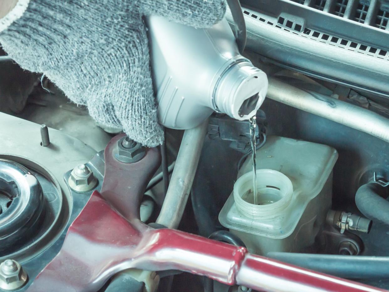 Car maintenance service, Close up of Auto mechanic pouring new brake fluid to car engine.