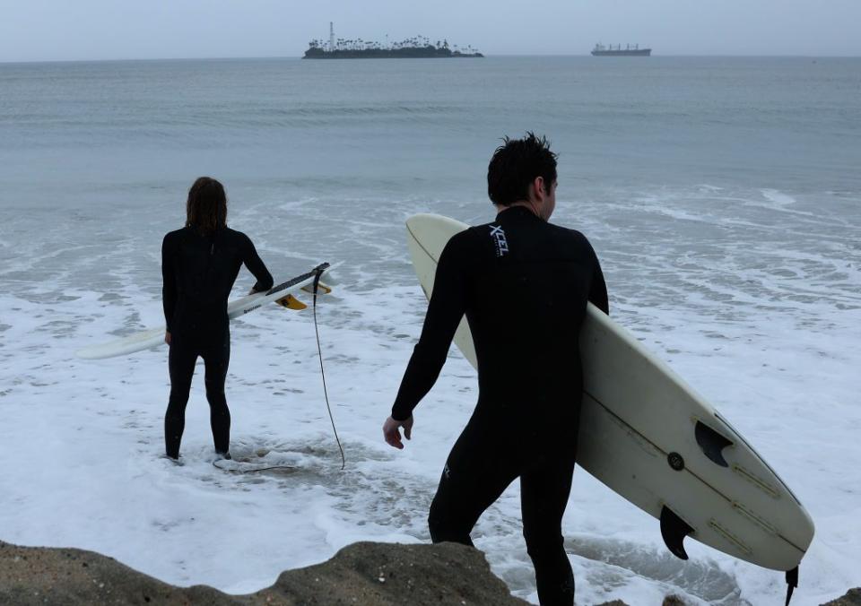 Surfers prepare to go in the water at Belmont Shore Beach on Sunday. The surf was rising as Tropical Storm Hilary headed toward Southern California.