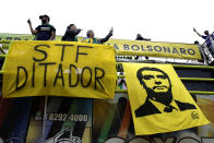 Supporters of Brazil's President Jair Bolsonaro stand above a sign referring to the Supreme Court as a dictator, and a banner depicting Bolsonaro during a protest against former Justice Minister Sergio Moro and the Supreme Court, in Brasilia, Brazil, Saturday, May 9, 2020. The Brazilian Supreme Court has authorized an investigation which could lead to Bolsonaro being accused of obstruction of justice. (AP Photo/Eraldo Peres)