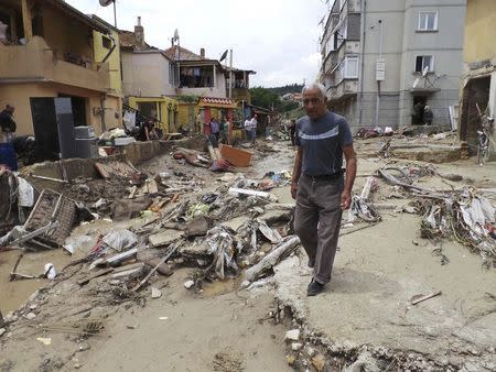 A man walks past debris on a street after heavy floods in Varna June 21, 2014. REUTERS/Impact Press Group