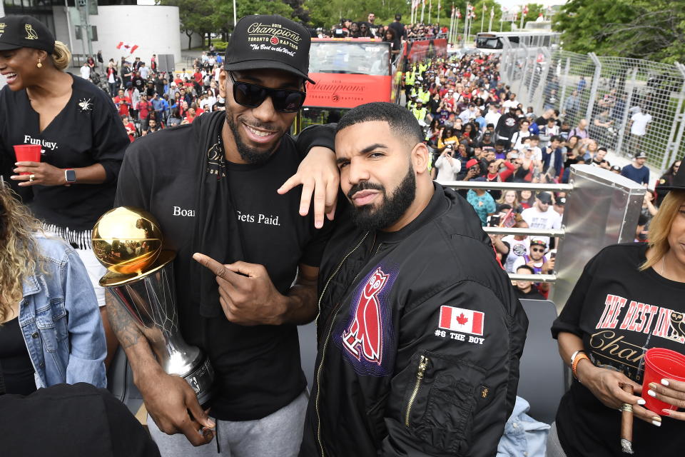 Toronto Raptors forward Kawhi Leonard points at his playoffs MVP trophy as he poses with performing artist Drake during the 2019 Toronto Raptors NBA basketball championship parade in Toronto, Monday, June 17, 2019. (Frank Gunn/The Canadian Press via AP)