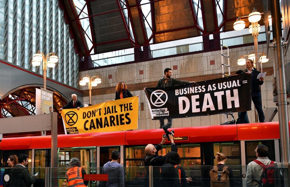 Demonstrators stand on top of a DLR train at Canary Wharf station on Thursday (Dylan Martinez/Reuters)