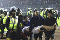 Soccer fans carry an injured man following clashes during a soccer match at Kanjuruhan Stadium in Malang, East Java, Indonesia, Saturday, Oct. 1, 2022. Panic following police actions left over 100 dead, mostly trampled to death, police said Sunday. (AP Photo/Yudha Prabowo)