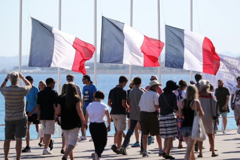 People pass French flags at half-mast in Nice on July 16, 2016, following the deadly Bastille Day attack