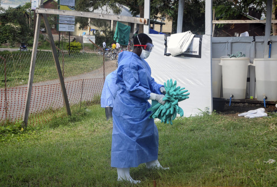 A medical worker carries a bunch of protective rubber gloves used to prevent infection, at the hospital where the first cross-border Ebola victim was isolated in the town of Bwera, near the border with Congo, in western Uganda, Thursday, June 13, 2019. The Congolese pastor who is thought to have caused the Ebola outbreak's spread into Uganda was unknown to health officials before he died of the disease, the World Health Organization's emergencies chief said Thursday, underlining the problems in tracking the virus. (AP Photo/Ronald Kabuubi)