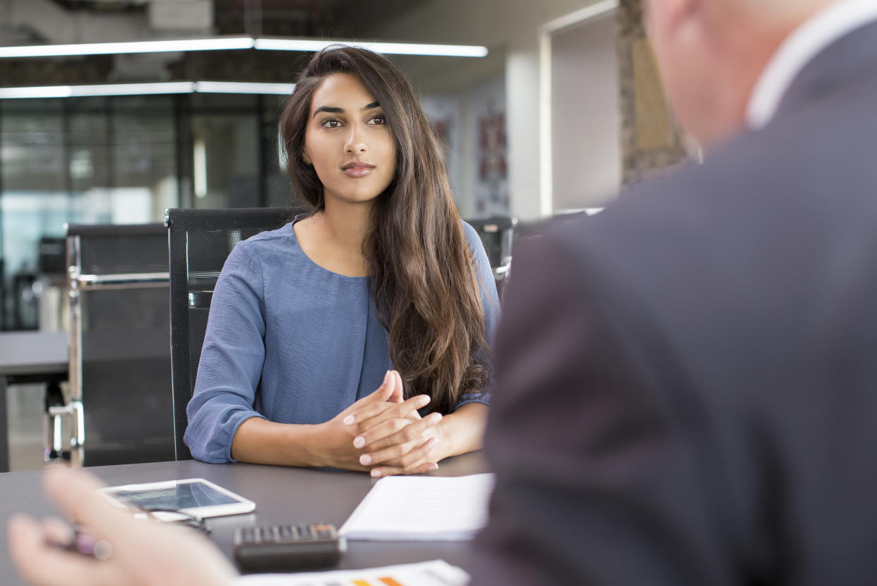 Focused Indian female customer meeting with financial advisor. Young beautiful candidate at job interview in modern office space. Business consulting or employment concept