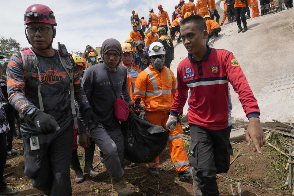 Rescuers carry the body of an earthquake victim recovered from under the rubble of a collapsed building in Cianjur, West Java, Indonesia,Tuesday, Nov. 22, 2022. Rescuers on Tuesday struggled to find more bodies from the rubble of homes and buildings toppled by an earthquake that killed a number of people and injured hundreds on Indonesia's main island of Java. (AP Photo/Tatan Syuflana)