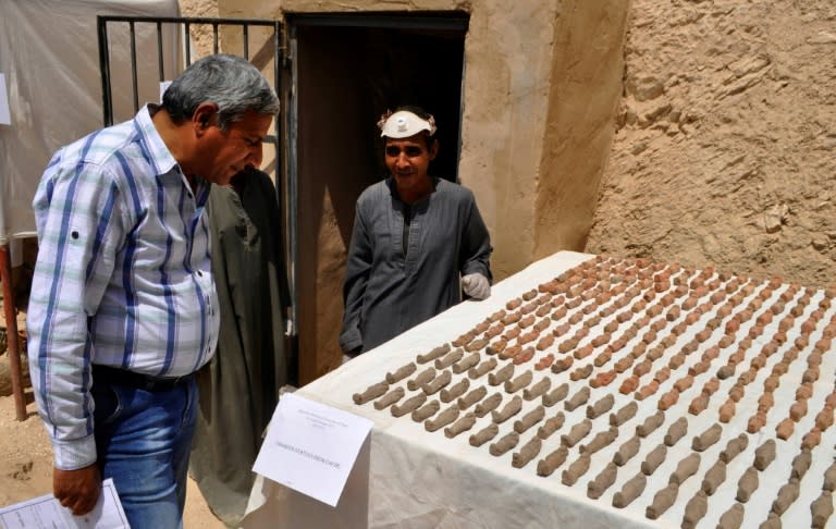 A member (R) of an Egyptian archaeological team stands near artifacts discovered in a 3,500-year-old tomb in the Draa Abul Nagaa necropolis, near the southern city of Luxor, on April 18, 2017