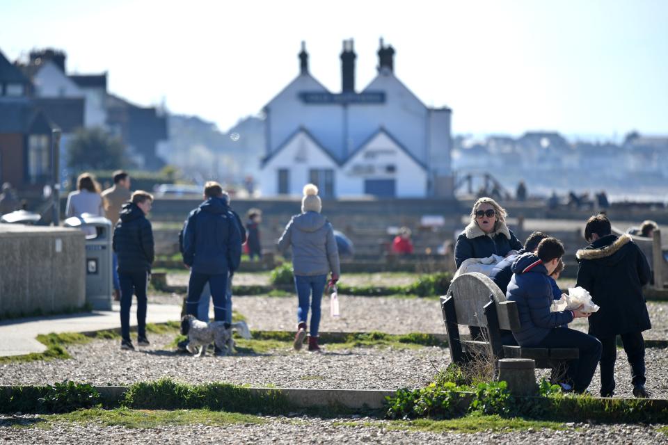 People enjoy the Spring sunshine on the seafront at Whitstable, east of London on Mother's Day, March 22, 2020. - Up to 1.5 million vulnerable people in Britain, identified as being most at risk from the coronavirus epidemic, should stay at home for at least 12 weeks, the government said Sunday. (Photo by Ben STANSALL / AFP) (Photo by BEN STANSALL/AFP via Getty Images)